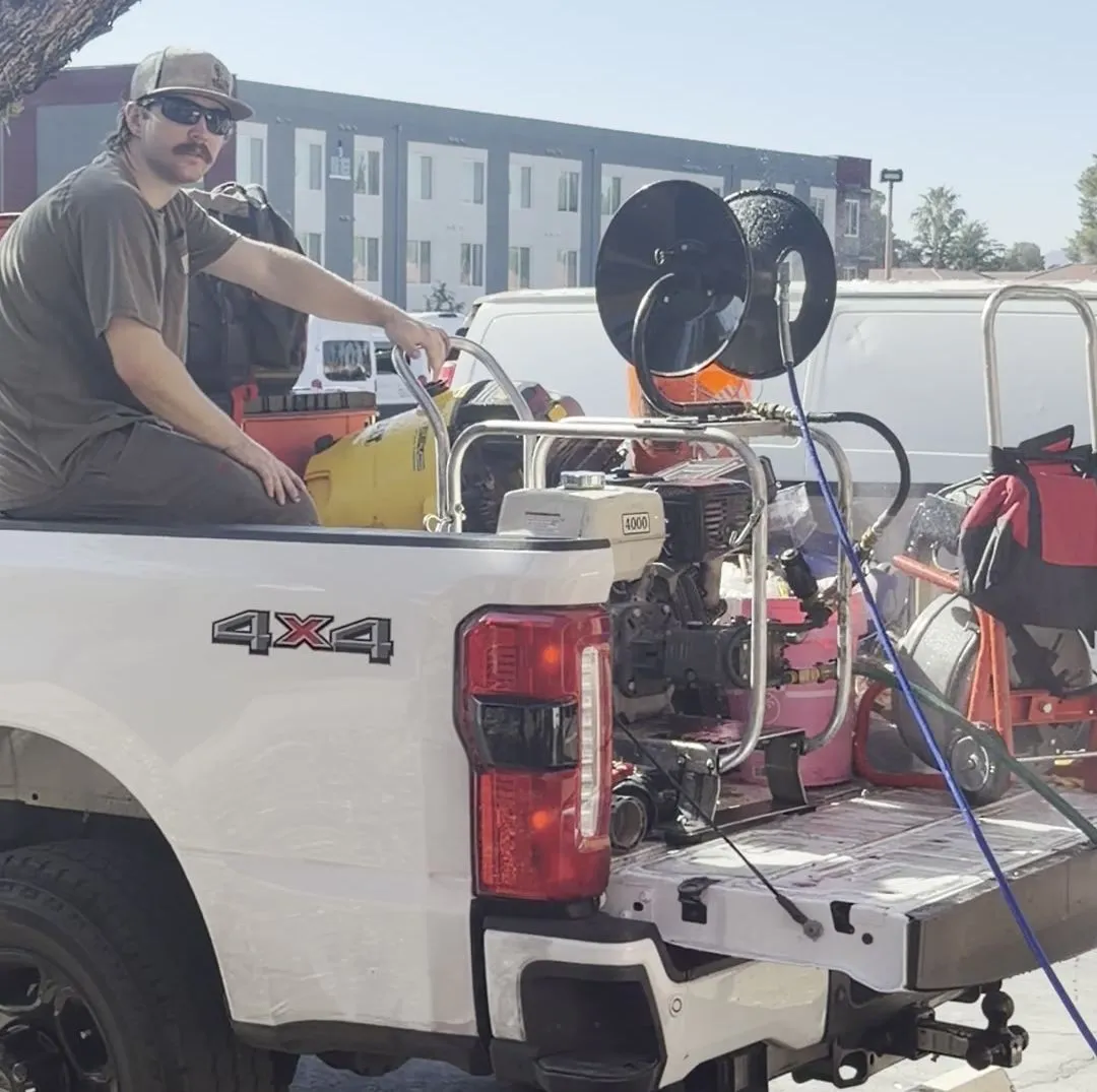 Plumbing tech with a hydro jetter mounted on the back of a pickup