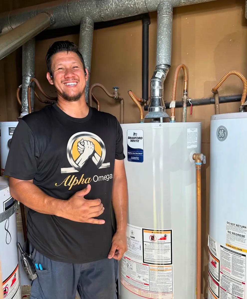Plumbing company owner smiling next to newly installed water heaters