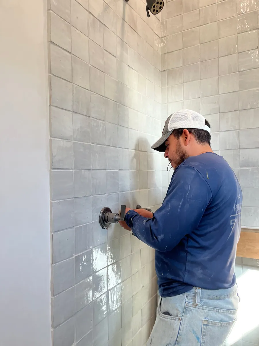 Plumbing tech installing a shower valve in a tiled wall