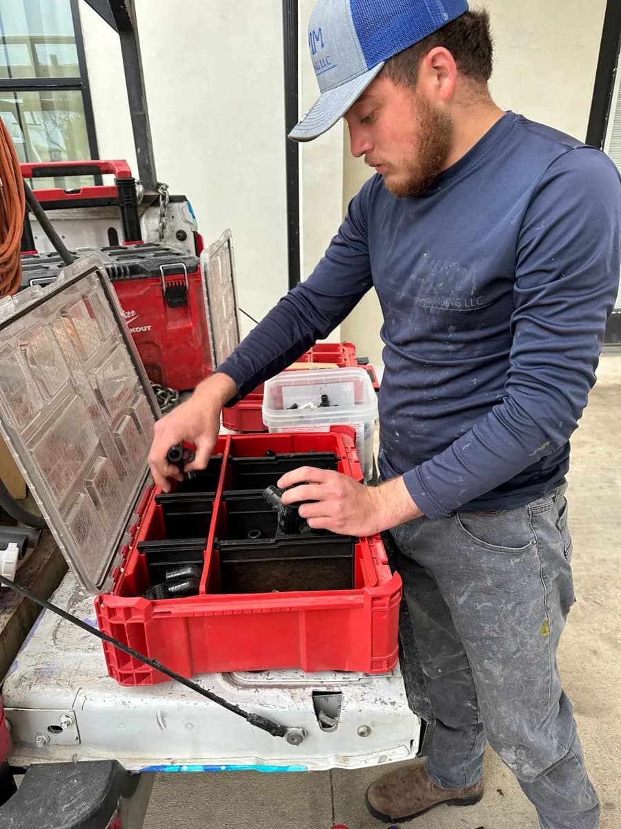 Plumbing tech pulling parts from an organized bin in the work truck