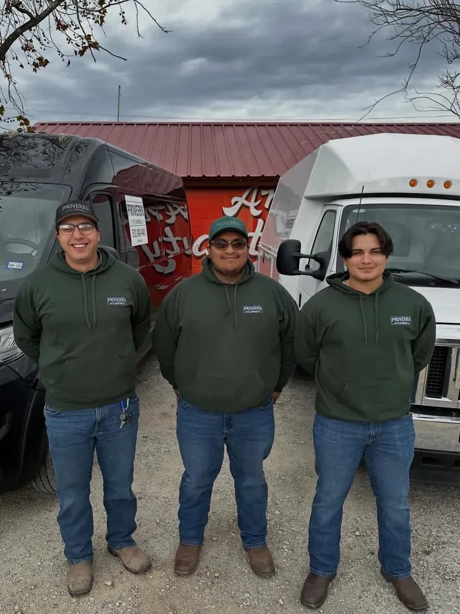 Plumbing team in matching uniforms in front of their service vans
